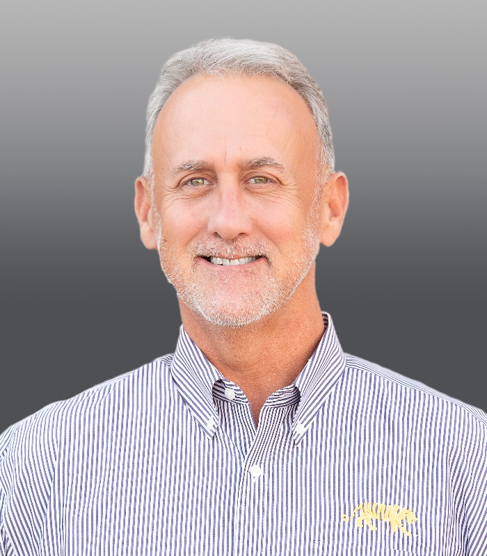 Meet Our Team - Professional and Welcoming Group at a Conference Table Faces the Camera, Team Leader Sitting on the Table with Arms Folded
